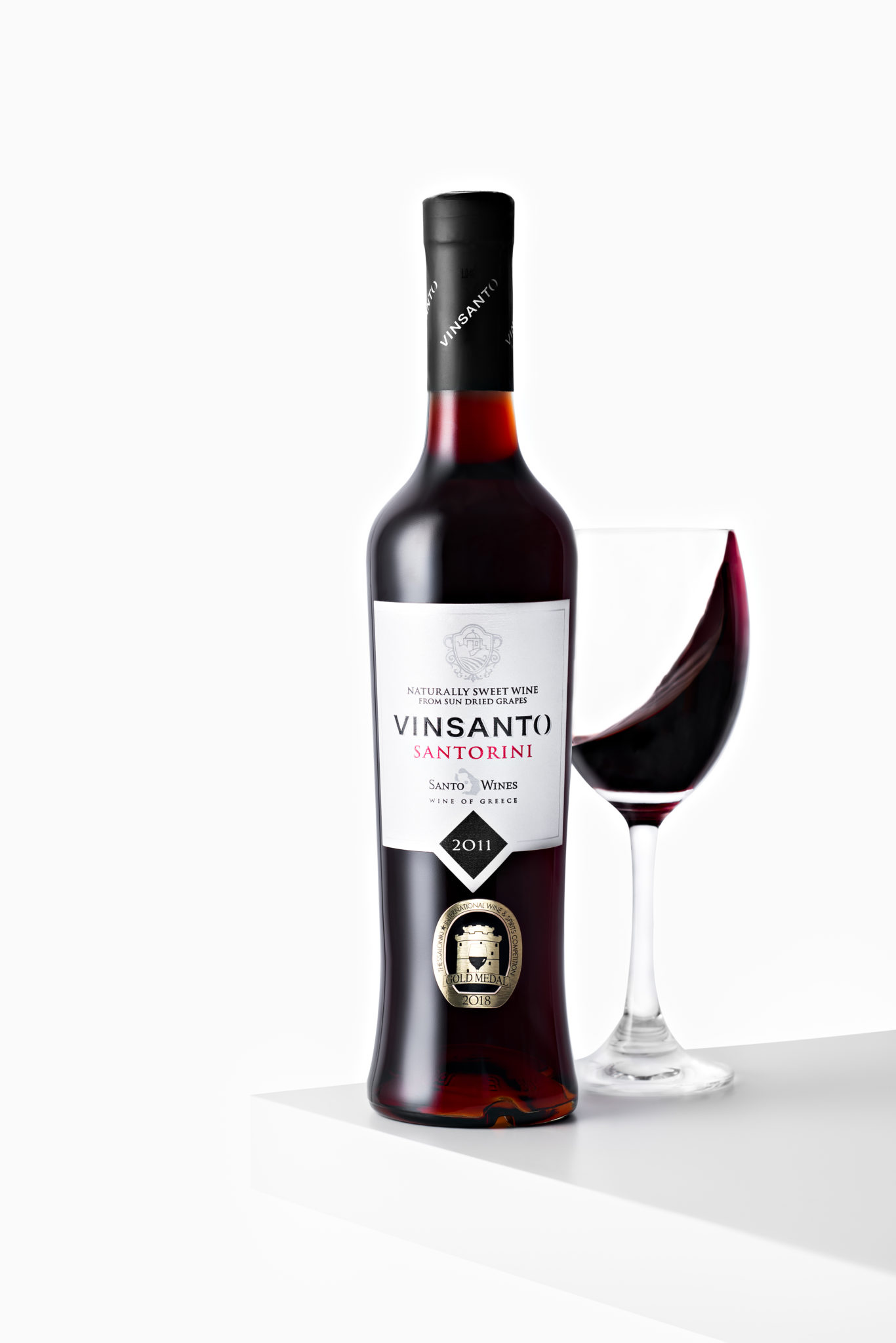 a bottle Santorini Vinsanto Red Wine beside a wine glass shot in studio