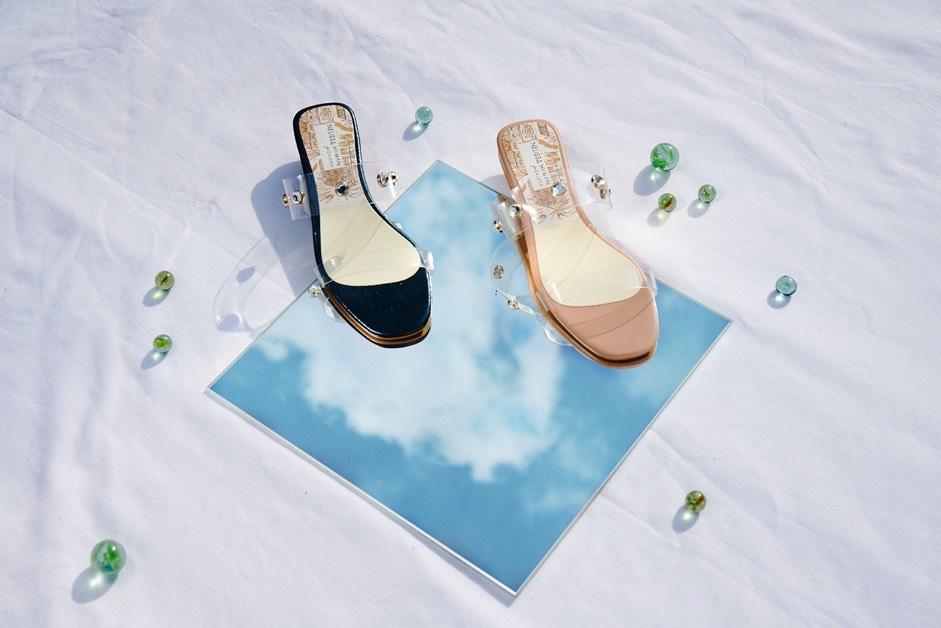 a pair of women shoes in different colours on a mirror reflecting teh sky